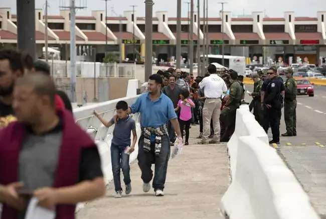 Migrants walk across International Bridge Two into Mexico from Laredo. They requested asylum in the United States but were returned to Mexico to await their court proceedings. Image by Miguel Gutierrez Jr. United States, 2019.