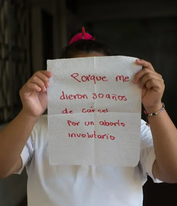 Evelyn Hernández, 20.</p>
<p>The napkin reads: 'because I was sentenced to 30 years in prison for an involuntary abortion.' Thinks frequently about suicide since she was arrested in 2016 after having a miscarriage. She has a hard time believing that she will spend 30 years locked up in the Ilopango Women's Prison in San Salvador. She says that her mother is the only one who visits her: 'I do not want my brothers to enter this place.'</p>
<p>Image by Almudena Toral. El Salvador, 2018.
