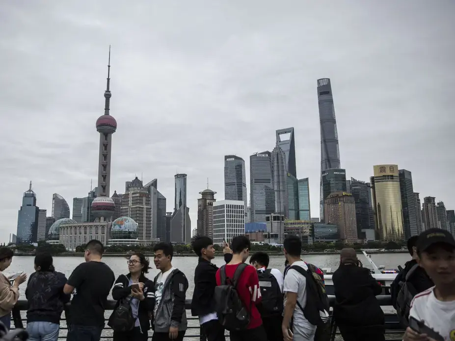 Tourists visiting The Bund line up along the railing facing the Huangpu River and Shanghai's Pudong business district to take photos on Saturday, September, 30, 2017, in Shanghai. Image by Kelsey Kremer. China, 2017.