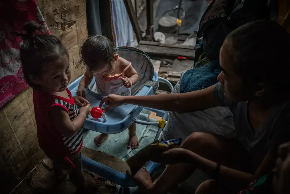 To earn money, Jasmine Durana’s sister, Joanna, and her mother, Vicky, take care of children during the day in their house. Image by James Whitlow Delano. Philippines, 2018. 