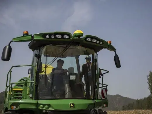 Two men take a look inside a John Deere combine on display during the groundbreaking ceremony or the China-US Demonstration Farm on Saturday, Sept. 23, 2017, in Luanping County, Hebei, China. Image by Kelsey Kremer. China, 2017.