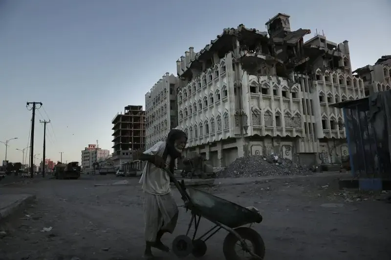 In this Feb. 13, 2018, photo, a elderly man walks past a damaged building from the 2015 war in Aden, Yemen. Violence, famine and disease have ravished the country of some 28 million, which was already the Arab world’s poorest before the conflict began. Image by Nariman El-Mofty. Yemen, 2018. </p>
<p>