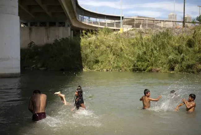 Migrants swim and wash clothes in the Rio Grande under the Gateway International Bridge in Matamoros. Image by Miguel Gutierrez Jr. Mexico, 2019.