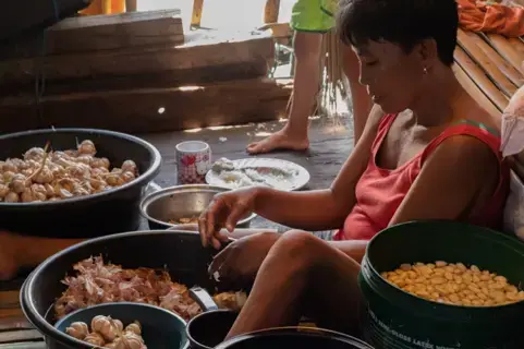 Peeling garlic sold to fast food restaurants has become a popular job in squatter areas like Isla Puting Bato. Image by Micah Castelo. Philippines, 2019