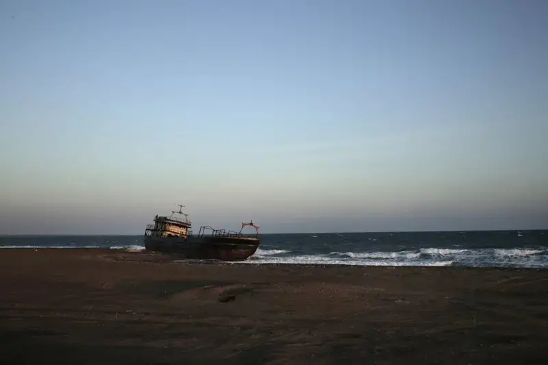This Feb. 10, 2018, photo shows a shipwreck abandoned on the shore from Mocha to Aden in Yemen. On the beach, old pleasure venues also lie empty, broken and deserted due to the civil war here. A shattered night club and a vacant children’s theme park are ghostlike reminders of generations past. Image by Nariman El-Mofty. Yemen, 2018. </p>
<p>