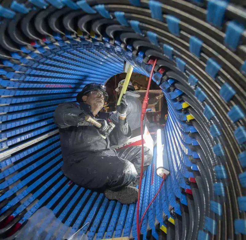 a worker does repairs inside a tube of fiber optic cables