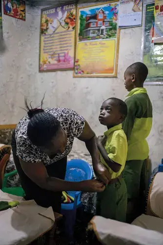 Elizabeth Mumo prepares her sons—Samuel, center, and Joshua—for school at the Kiserian Bridge school. She says she has high hopes for Joshua: ‘‘I can see Oxford.’’ Image by Diana Zeyneb Alhindawi for The New York Times. Kenya, 2017.<br />
