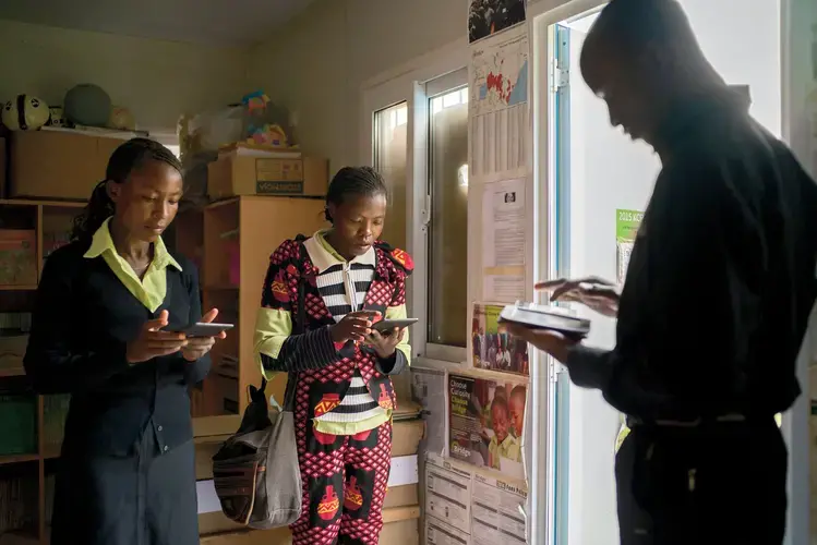 Bridge teachers at a school in Kiserian, Kenya, receiving their lesson plans via e-readers. Image by Diana Zeyneb Alhindawi for The New York Times. Kenya, 2017.<br />
