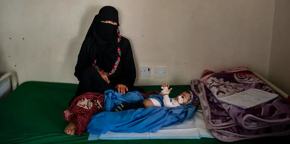 Kafaya, whose name means “enough,” lies next to her mother on May 7, 2018, in Bani Mansur, Yemen. Image by Alex Potter. Yemen, 2018. 