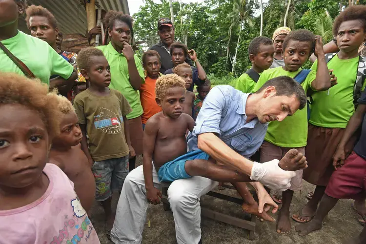 Oriol Mitjà, whose work has triggered a new yaws eradication effort, examines a young patient named Jeremiah, who has an active infection, but can be cured with a dose of azithromycin. Image by Brian Cassey. Papua New Guinea, 2018. 