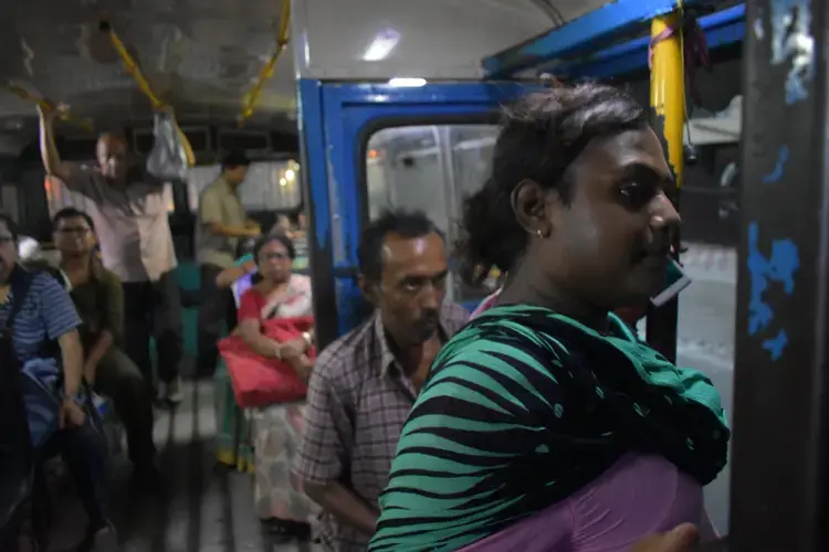 Sintu, like many transgender individuals, relies on street economies such as dancing for survival. Traveling all across Kolkata, she spends a large portion of her life on public transportation. Buses and trains across India are divided by gender with painted signs. There is only standing room on this bus, but she always sits in the 'Gentlemen's' section. Image by Siyona Ravi. India, 2017.
