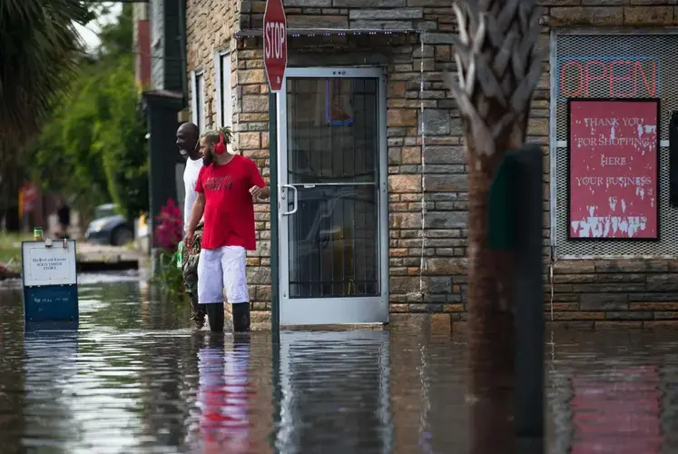 People walk out of President Market during flooding on Wednesday, May 20, 2020, in Charleston. The market is just across from the Gadsden Green public housing complex. Image by Andrew Whitaker / The Post and Courier. United States, 2020.</p> <p>