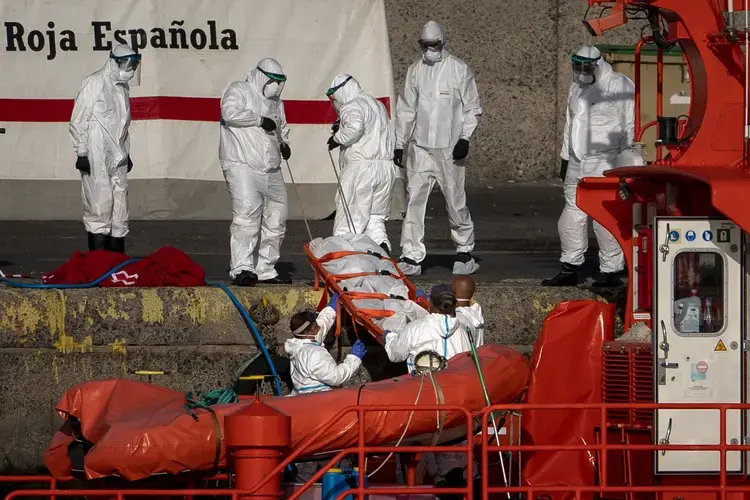 Emergency workers carry a migrant’s body after being found dead by the Spanish Maritime Rescue Service, at the Arguineguin port in Gran Canaria island, Spain, on Friday, Aug. 21, 2020. Image by Emilio Morenatti/AP Photo. Spain, 2020..jpeg