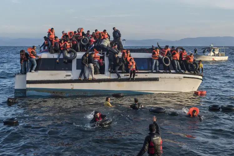 Syrian and Iraqi refugees arrive from Turkey to Skala Sykamias, Lesbos island, Greece. Spanish volunteers (life rescue team with yellow-red clothes) are from 'Proactiva open arms.' Image courtesy Ggia / Creative Commons 4.0.