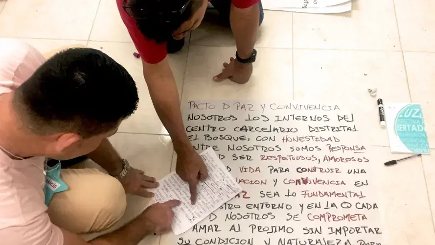 Inmates at El Bosque penitentiary in Barranquilla, Colombia, write out their commitment to peace and co-existence at the end of a workshop on conflict resolution in August 2018. Image by Verónica Zaragovia. Colombia, 2018.