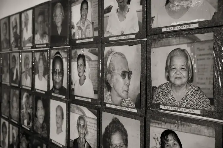 Images of the estimated 1,000 Philippine 'comfort women' who were enslaved and sexually victimized by the Japanese Imperial Army during World War II fill a wall at the offices of Lila Pilipina. The organization of World War II victims of sexual war crimes has helped the 'comfort women' in their fight for compensation. Image by Cheryl Diaz Meyer. Philippines, 2019.