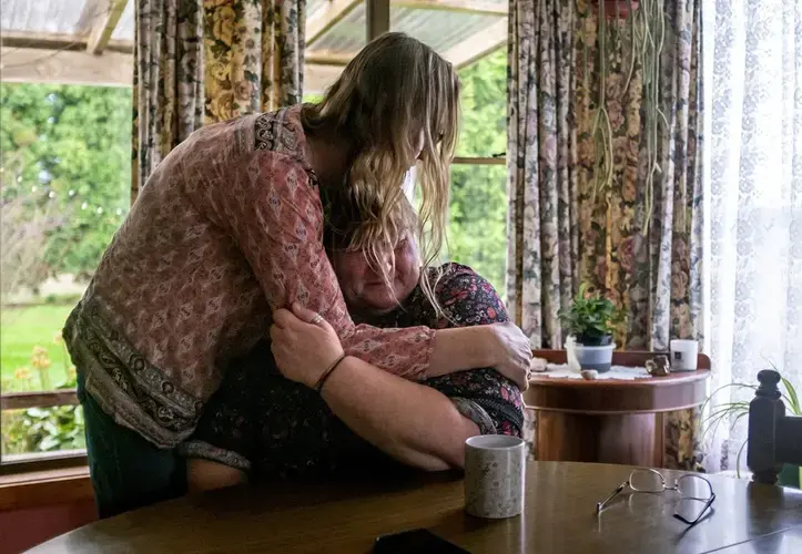 Carmall Casey, right, is embraced by Maxine Piper, a longtime friend and a source of support through Casey's addiction to opioids and battle with chronic pain, at her home in Black River, Tasmania, Australia, Tuesday, July 23, 2019. Casey doesn't know what she'll do when the pain returns. But she says she will never return to opioids. 'I'm not going back,' she says and begins to weep. 'I'm not.' Image by David Goldman. Australia, 2019.
