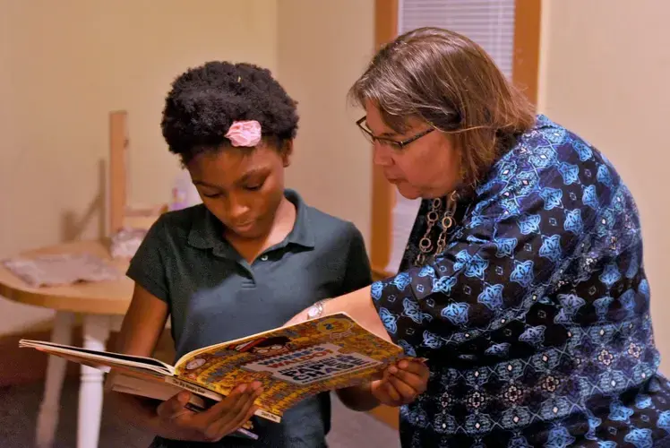 Jasmine, 11, looks at a book with Beth Mixson from Family Promise of Jacksonville in this 2015 file photo. Family Promise, which provides temporary assistance, hospitality, and case management for homeless families with children, helped Jasmine and her grandmother move into a home. Image by Bob Mack / Florida Times-Union. United States, 2015.