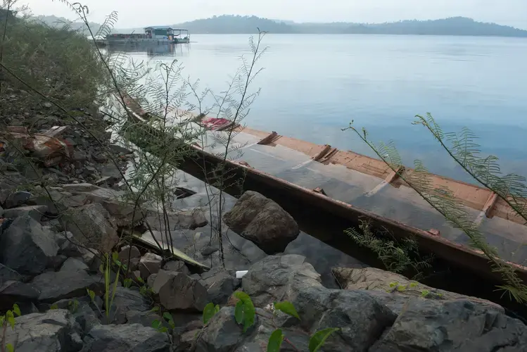 A broken boat sits by the shoreline of the Brokopondo Reservoir. In order to provide water for the Afobaka Dam, some 600 square miles were flooded, with historians citing 43 Saamaka villages in the area of the flooding. The 6,000 residents, including the family of Frans Weewee, were relocated by the government. Image by Stephanie Strasburg. Suriname, 2017.