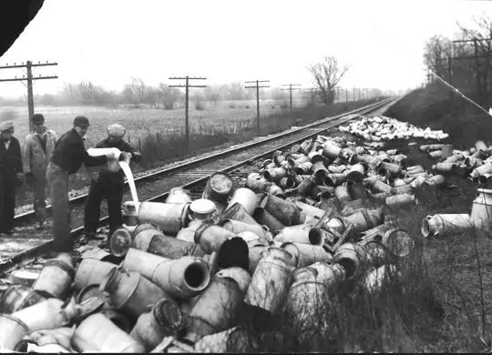 As the Great Depression took hold in the late 1920s, many farmers saw their milk prices drop and by 1933, prices were less than half what they had been just three years prior. Farmers reacted with milk strikes, and the protests often turned violent. This is the scene after a crowd of pickets stopped a Soo Line freight train near the city limits of Burlington by throwing ties across the tracks and firing shots. The pickets broke open seven cars and dumped the cans of milk along the tracks. Image courtesy of the Milwaukee Journal Sentinel archives.
