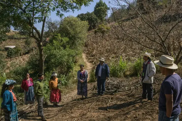 Sebastian Charchalac talks to villagers in a field in Paraje León. Trained agronomists, through grants, have been instructing rural communities in diversifying crops, conserving water, and reforesting some of the surrounding areas. Image by Mauricio Lima. Guatemala, 2019.