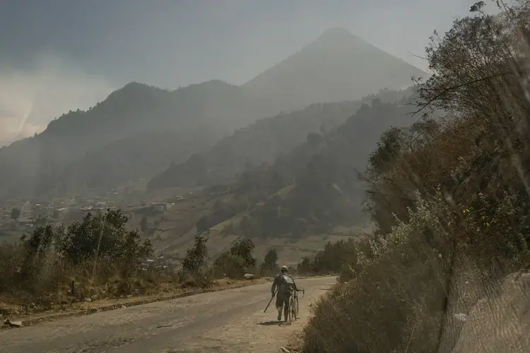 A villager walks along a road down the Siete Orejas mountain, outside the village of Xecaracoj, with the Santa María volcano in the background. Image by Mauricio Lima. Guatemala, 2019. 