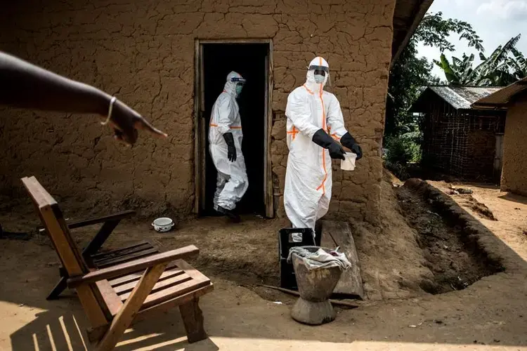 Ebola responders disinfect a home in Aloya in which three people have died. Image by John Wessels. Democratic Republic of Congo, 2019.<br />
