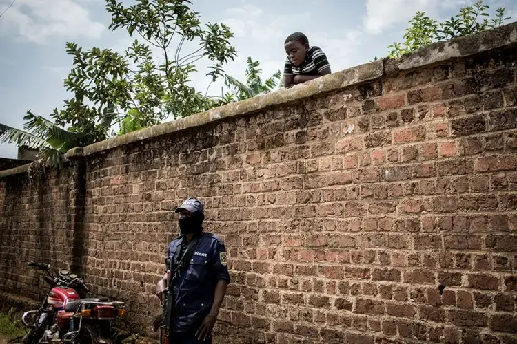 A police officer stands guard outside a clinic in Katwa. Image by John Wessels. Democratic Republic of Congo, 2019.<br />
