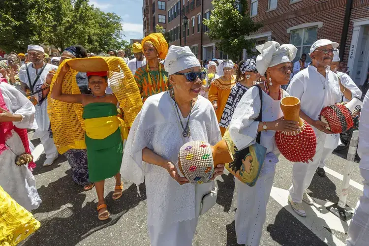 At the Odunde Festival of 2019, musicians played the African gourd instrument, a shekere, to lead the procession to the South Street Bridge where an offering would be made of fruits and flowers, tossed into the Schuylkill River. Michael Bryant / The Philadelphia Inquirer. United States, 2019.