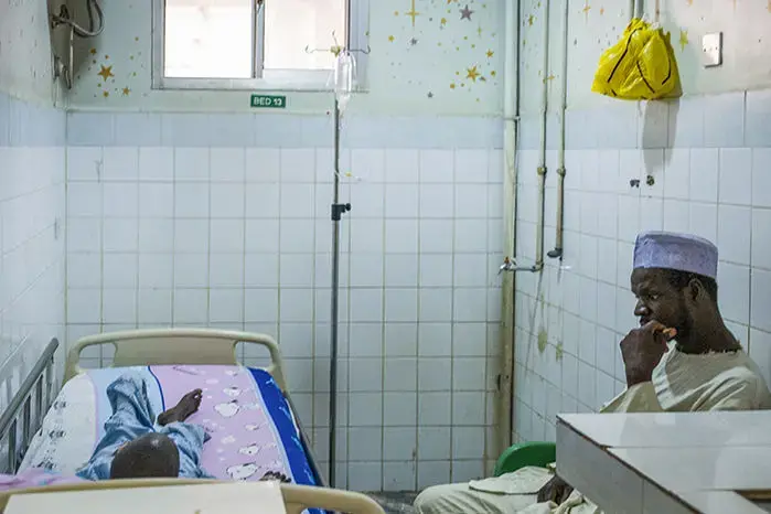 Ibrahim Adamu sits with his son Yusuf in an isolation room at Asokoro District Hospital in Abuja. Image by Misha Friedman. Nigeria, 2018. </p>
<p>