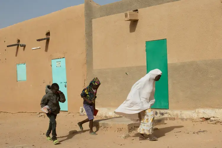 A woman and two children walk through strong winds in Agadez, Niger. Image by Joe Penney. Niger, 2018.