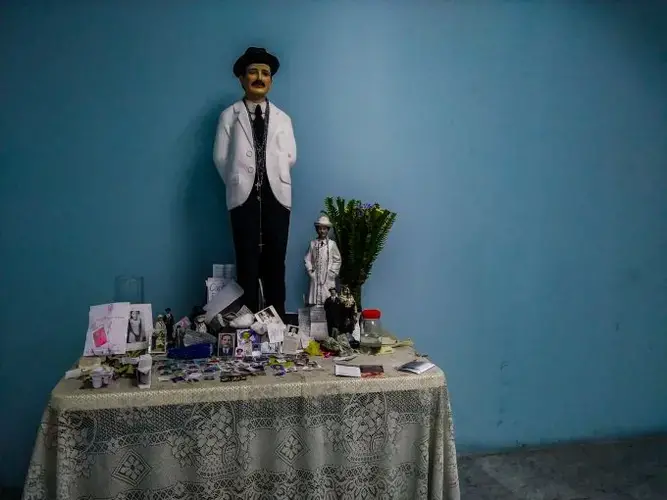 An improvised altar in honor of José Gregorio Hernández at the Hospital J.M de los Ríos. Hernández, a Venezuelan doctor widely known and remembered by his kindness and service to the poor, is considered a saint by many Catholics in Venezuela, who often think of him as the protector of the ill. At the pediatric hospital, mothers and family members put photos of their children at the altar to pray for their good health and swift recovery. Image by Flaviana Sandoval. Venezuela, 2018.