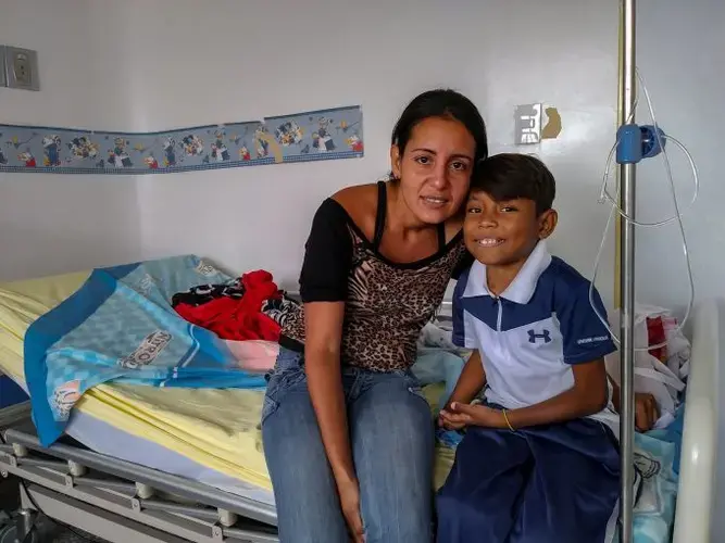 Emily Aguiar and her 12-year-old son, Eliécer Aguiar, at the Hospital J.M de los Ríos  in Caracas, where Eliécer remains hospitalized due to an infection in one of the stiches around his dialysis catheter. Eliécer suffers from severe kidney decease and needs a kidney transplant to survive. Image by Flaviana Sandoval. Venezuela, 2018.