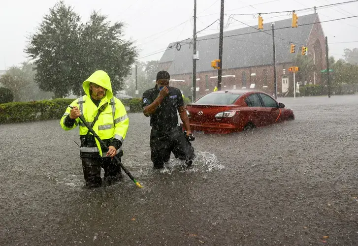 Charleston firefighter Viktor Kruzhinsky (left) uses a roof hook as a depth gauge to sound the ground in front of him while rescuing motorists trapped by floodwaters at the intersection of King and Huger streets after an intense downpour downtown Charleston Friday, Sep. 25, 2020. Andrew J. Whitaker/Post and Courier Staff. United States, 2020.