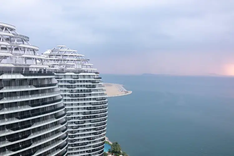 A view from on Phoenix island, Sanya, Hainan. Phoenix Island, on the resort city of Sanya, was the Hainan island’s first flagship land reclamation mega project, attracting internationally renowned architects. Reclaimed between 2002 and 2003, and opened for business in 2015, the artificial island in Sanya Bay has luxury apartments, hotels and a cruise centre—all a short distance from the centre of the city. A second phase of reclamation was undertaken in 2014—seen here as the empty, sandy plot—bringing the total size of the island to 0.84 square kilometers. But this was found to have led to the erosion of over 2km of Sanya Bay’s coast. Following an environmental inspection in late 2017, the government has slapped a suspension on further construction as the project was found to have impacted coastal erosion and the ecosystem, and caused sedimentation at the mouth of the Sanya River. Companies involved in this project include New York-based Balmori Associates, which does landscape and urban design, and the brand-name Chinese architect Ma Yansong's firm MAD. Image by Sim Chi Yin. China, 2018.