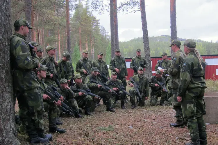 Two corporals debrief a platoon of mechanized infantry recruits after a day of training in movement to contact. Image by Teresa Fazio. Sweden, 2018.