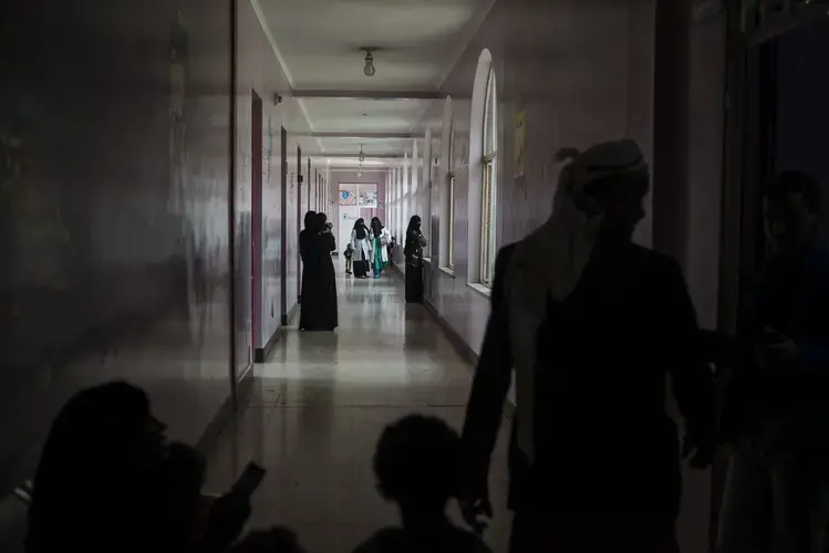 Yemeni families and nurses walk through the malnutrition wing at Sabaeen Hospital in Sanaa on May 4, 2018. Most hospitals in the north are functioning at minimal levels, constantly short on supplies, while their staff have remained unpaid for months. Image by Alex Potter. Yemen, 2018. 