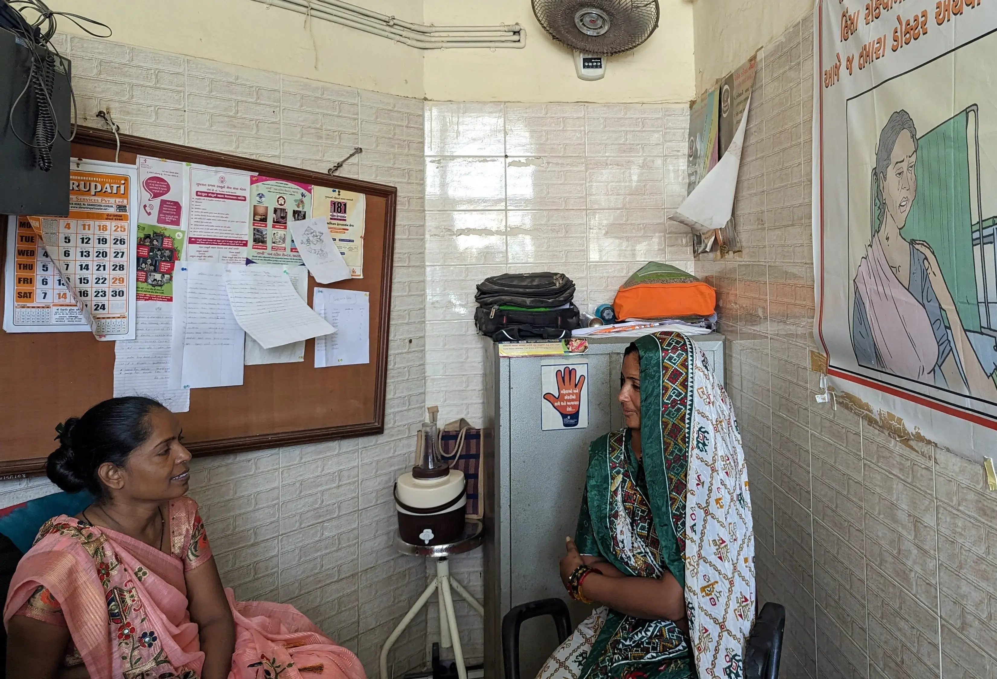 two women sit in an exam room in India.