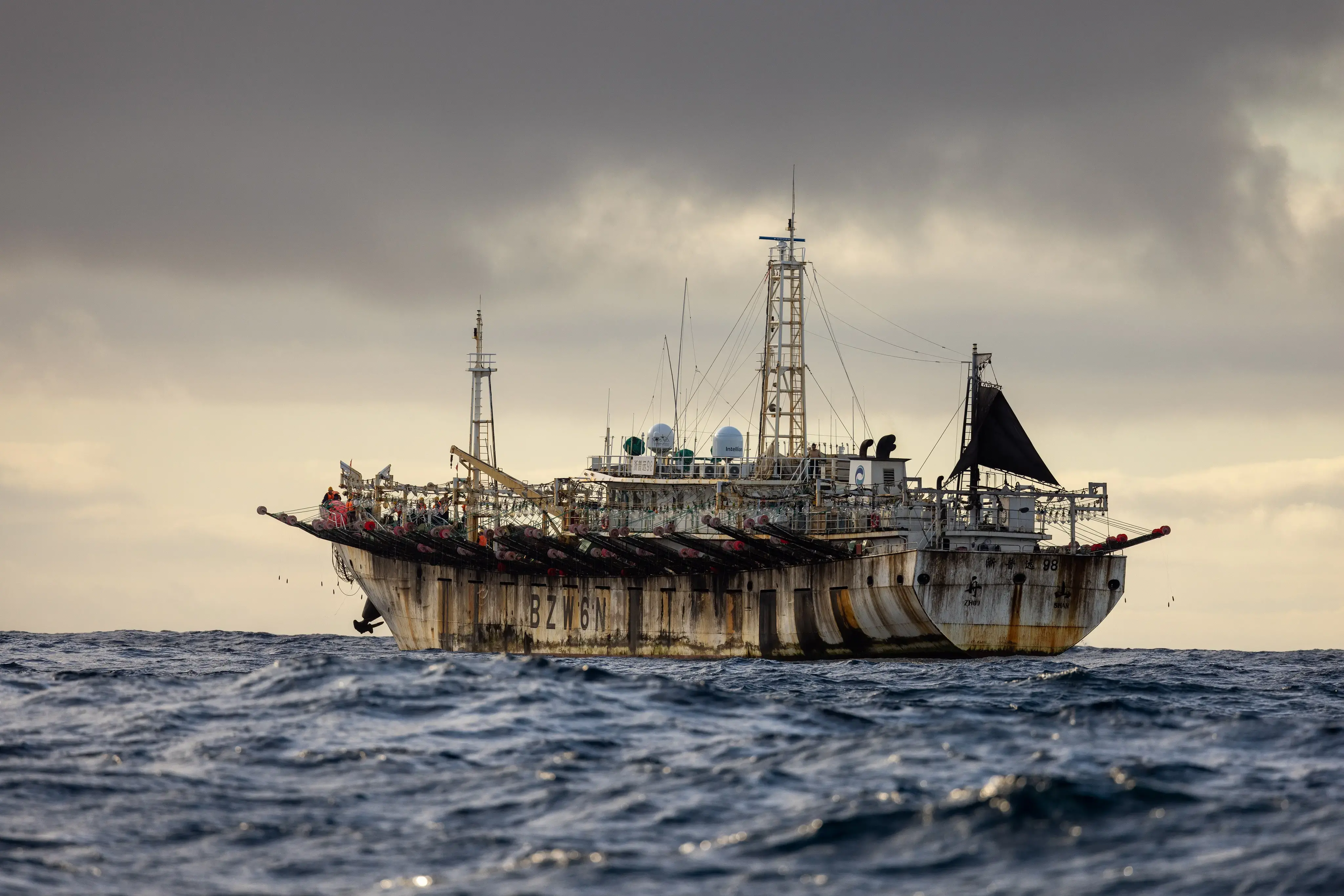 A fishing vessel floats on the open sea in cloudy weather