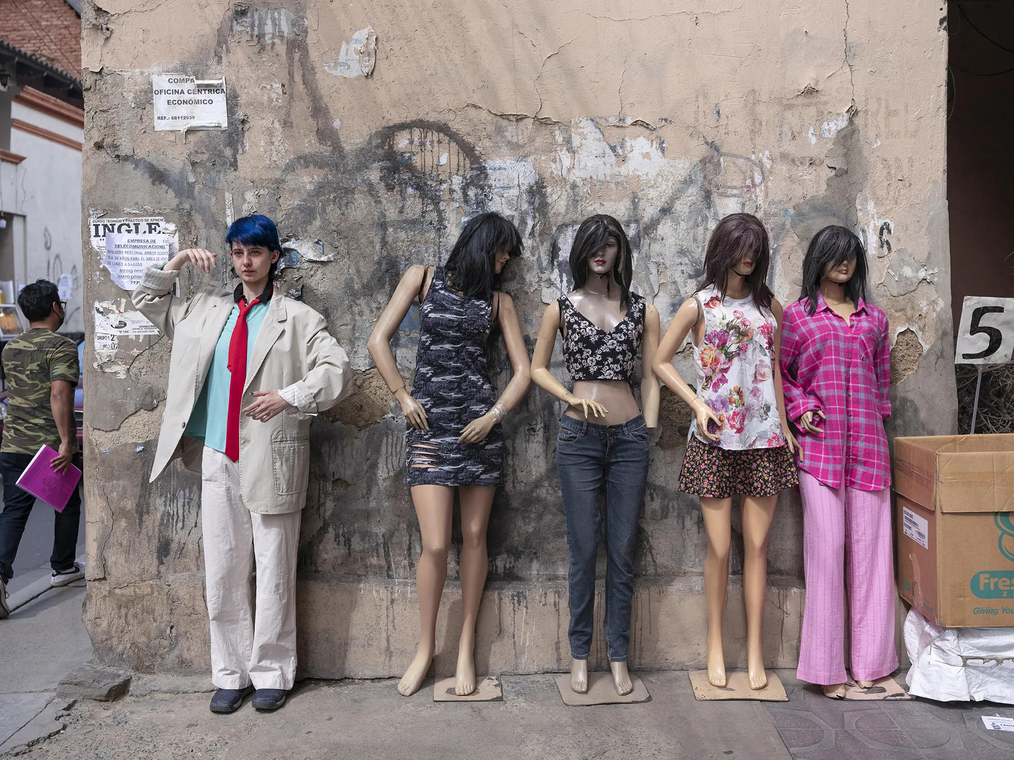 A young person poses next to mannequins on the street