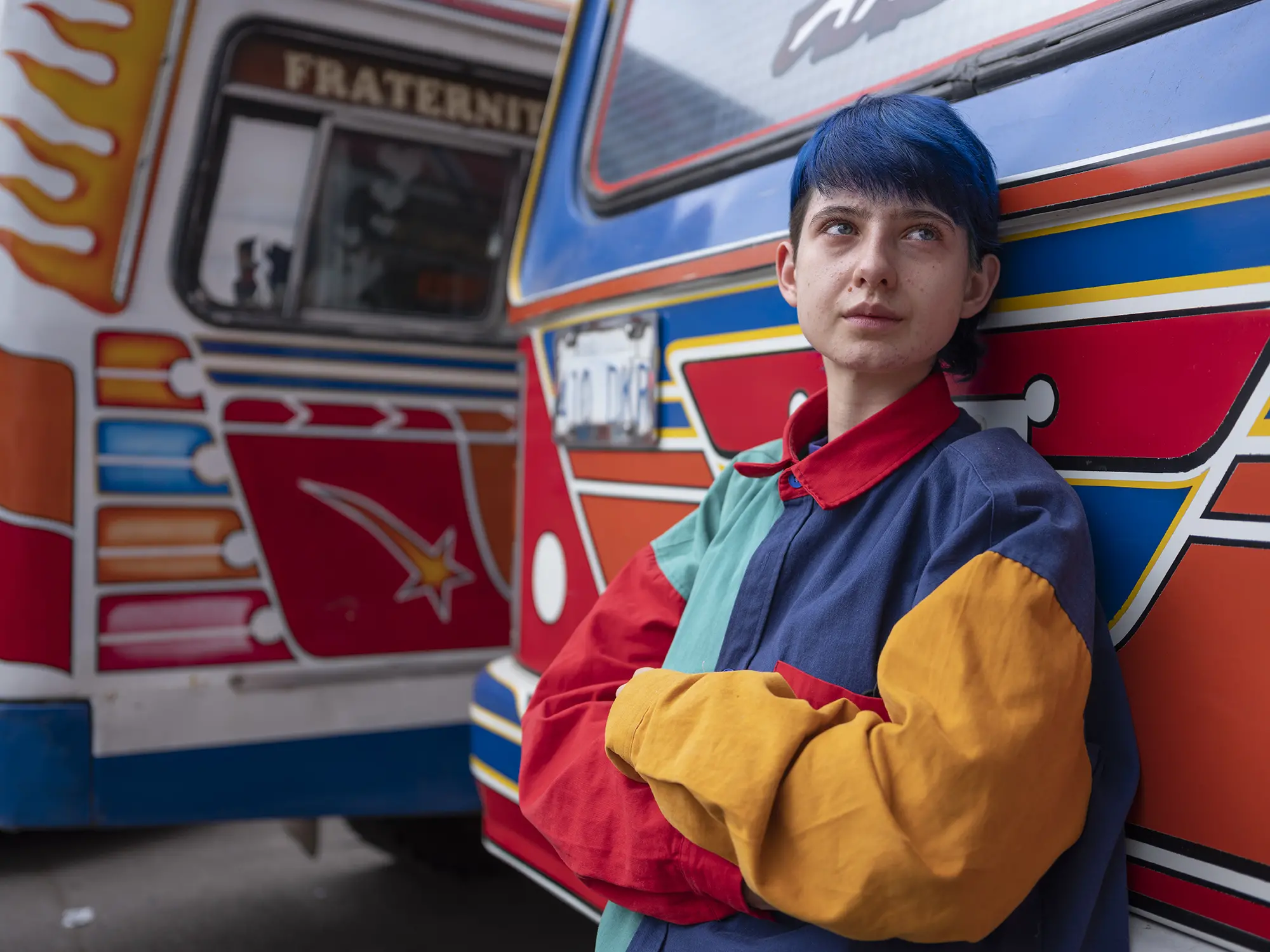 A young person poses next to a bus