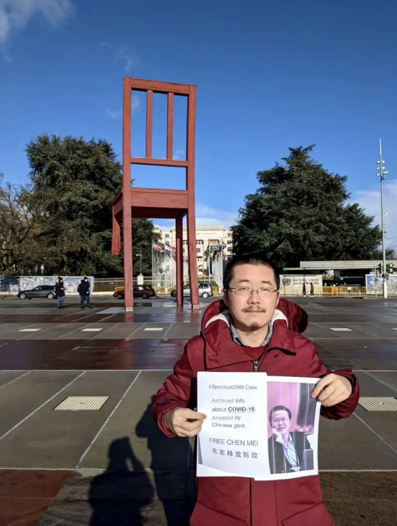 Chen Kun stands in front of United Nations holding a small poster of his brother with infomration about why he was arrested and the words "FREE CHEN MEI"