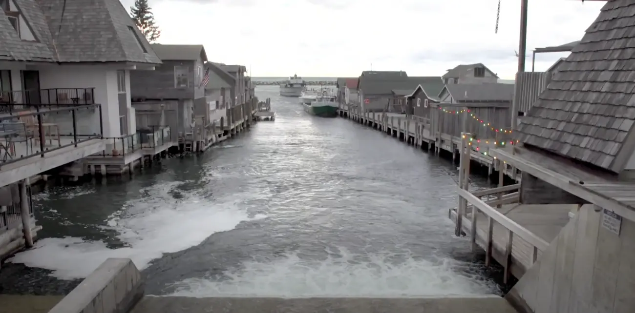 gray flood waters inundate a fishtown whose buildings are already on stilts.