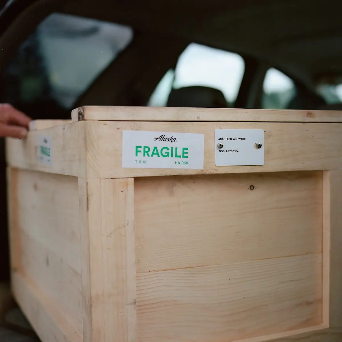 A plywood box with a green 'FRAGILE' label and Anastasia's name.