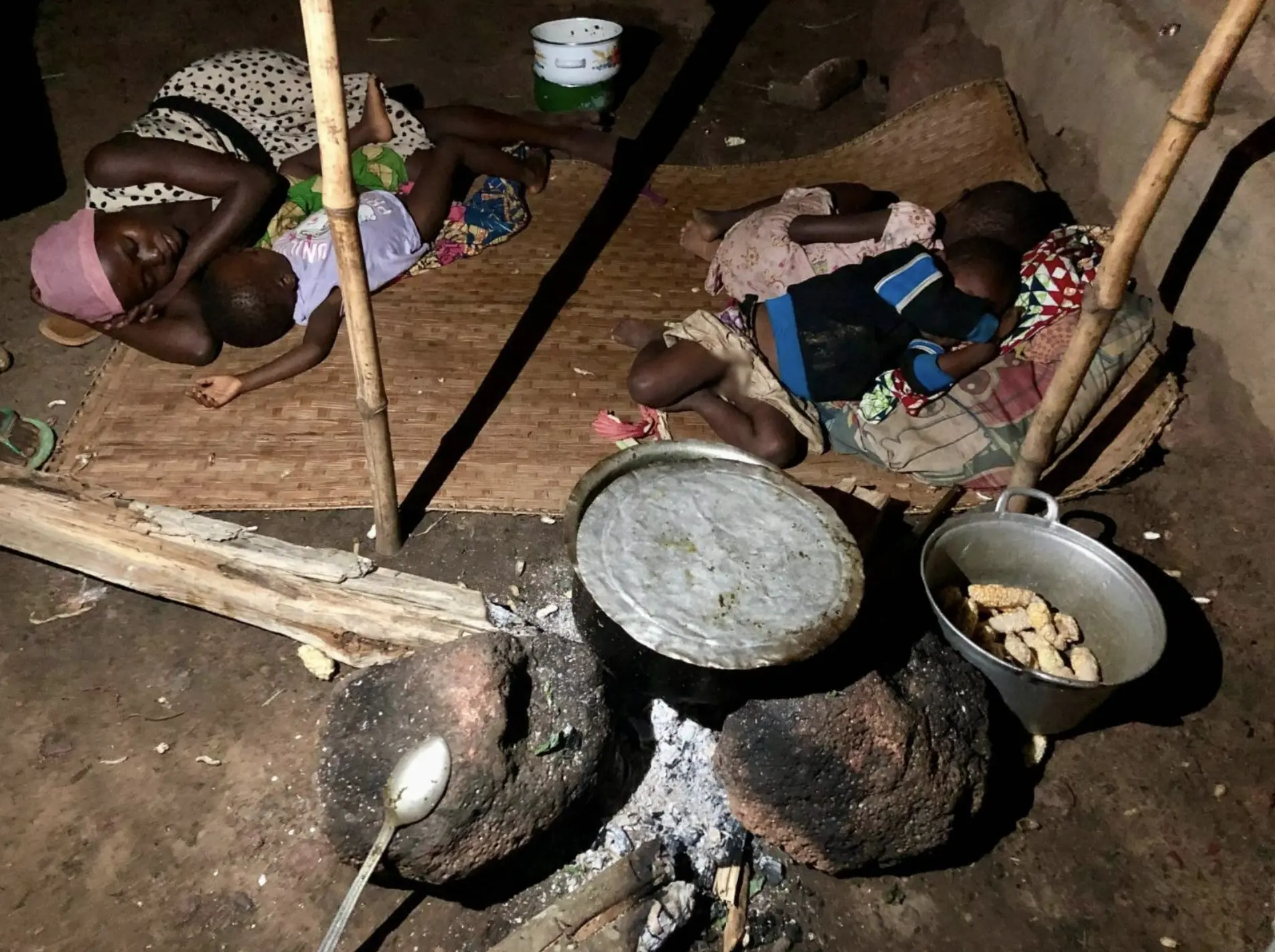 An employee’s family sleeps outside after eating a meager meal of cassava leaves and a handful of corn.