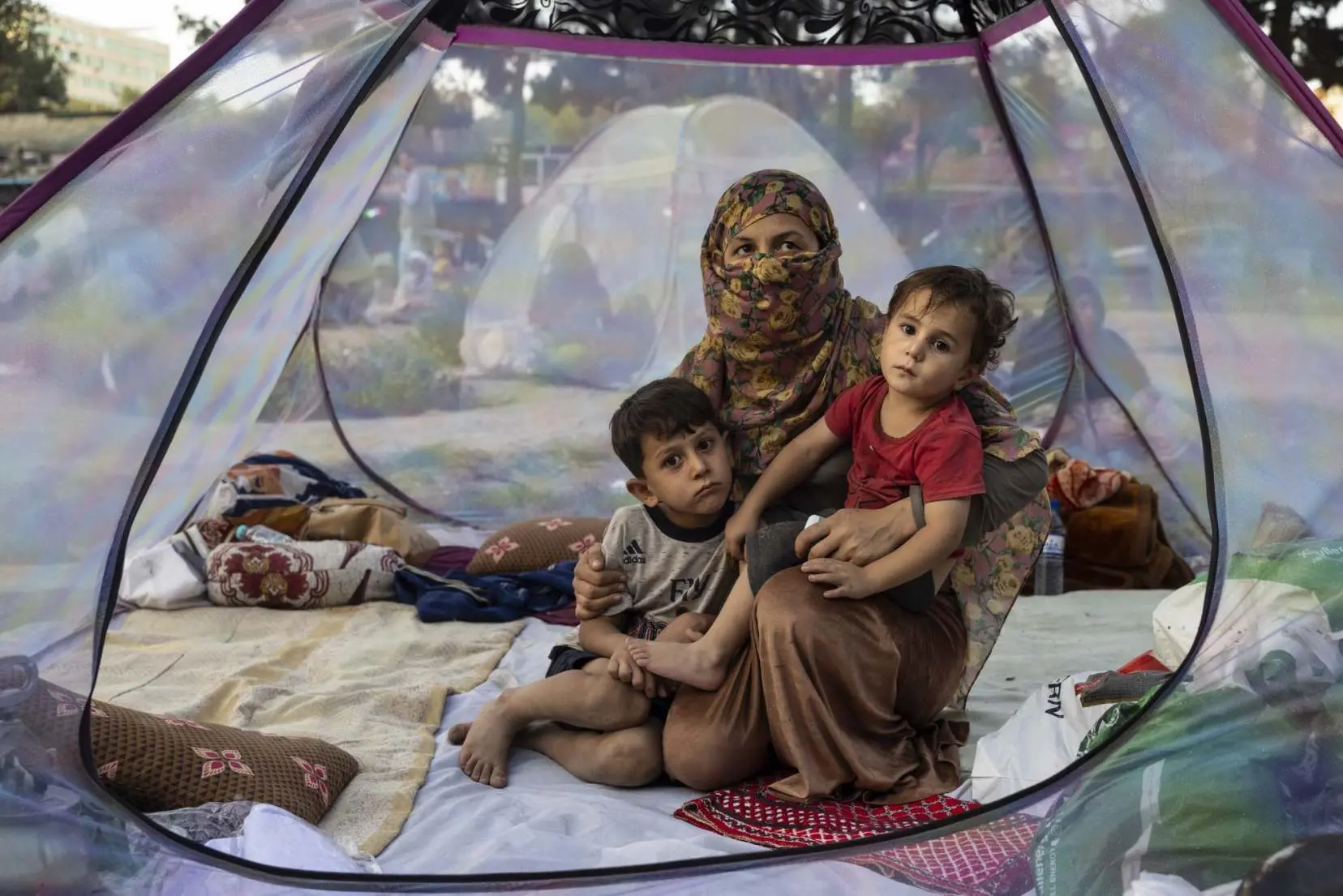 Woman sits in a tent with her children