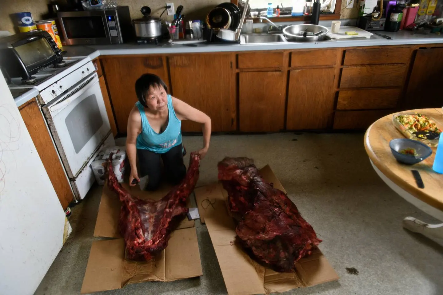 Another Emmonak resident cuts moose meat in her home.