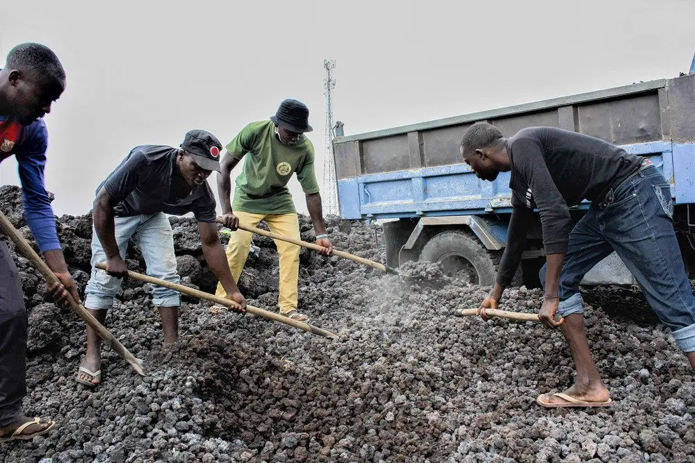 Men shovel gravel made from hardened lava rocks into trucks in Goma