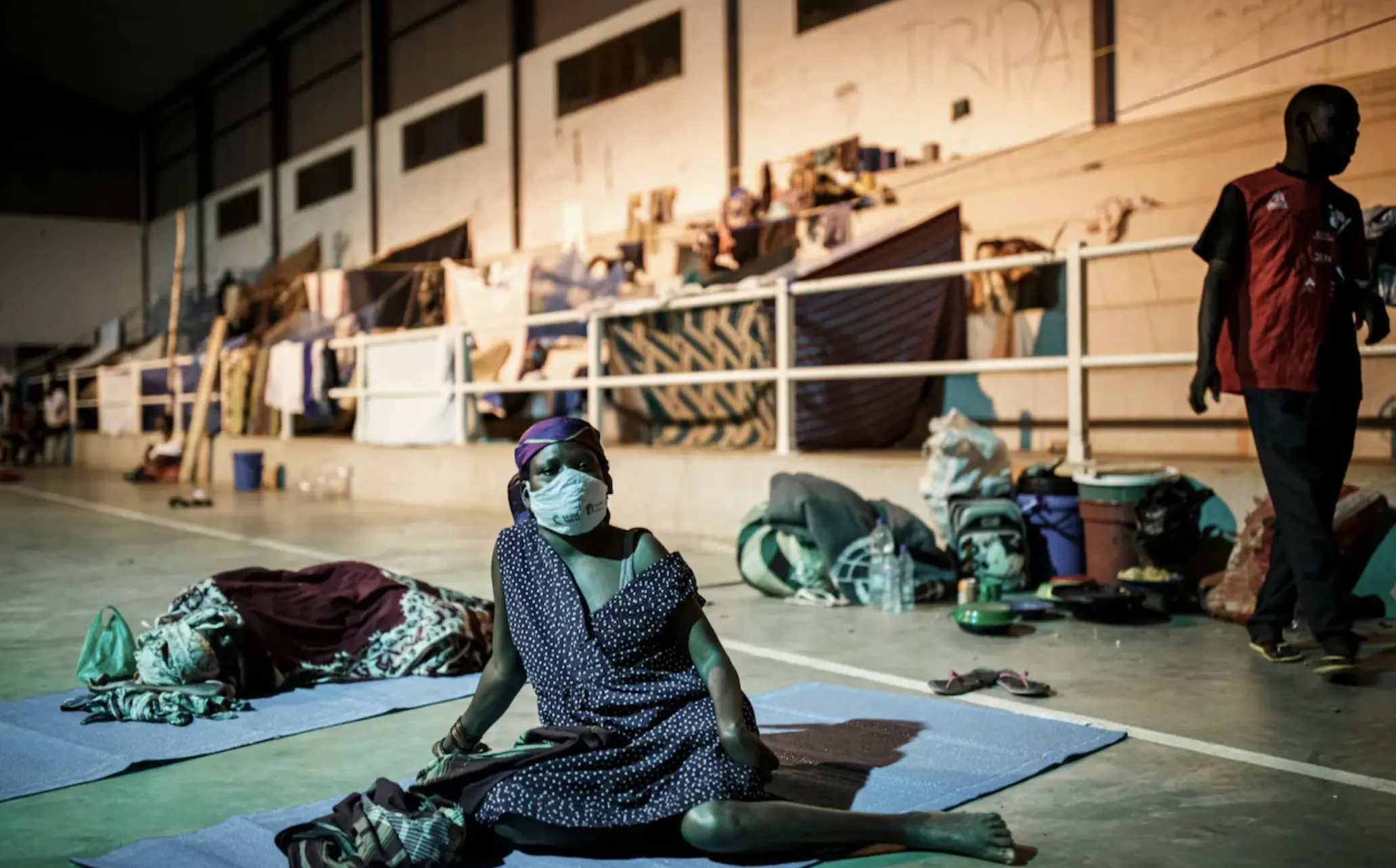 A woman sits masked in a sports complex