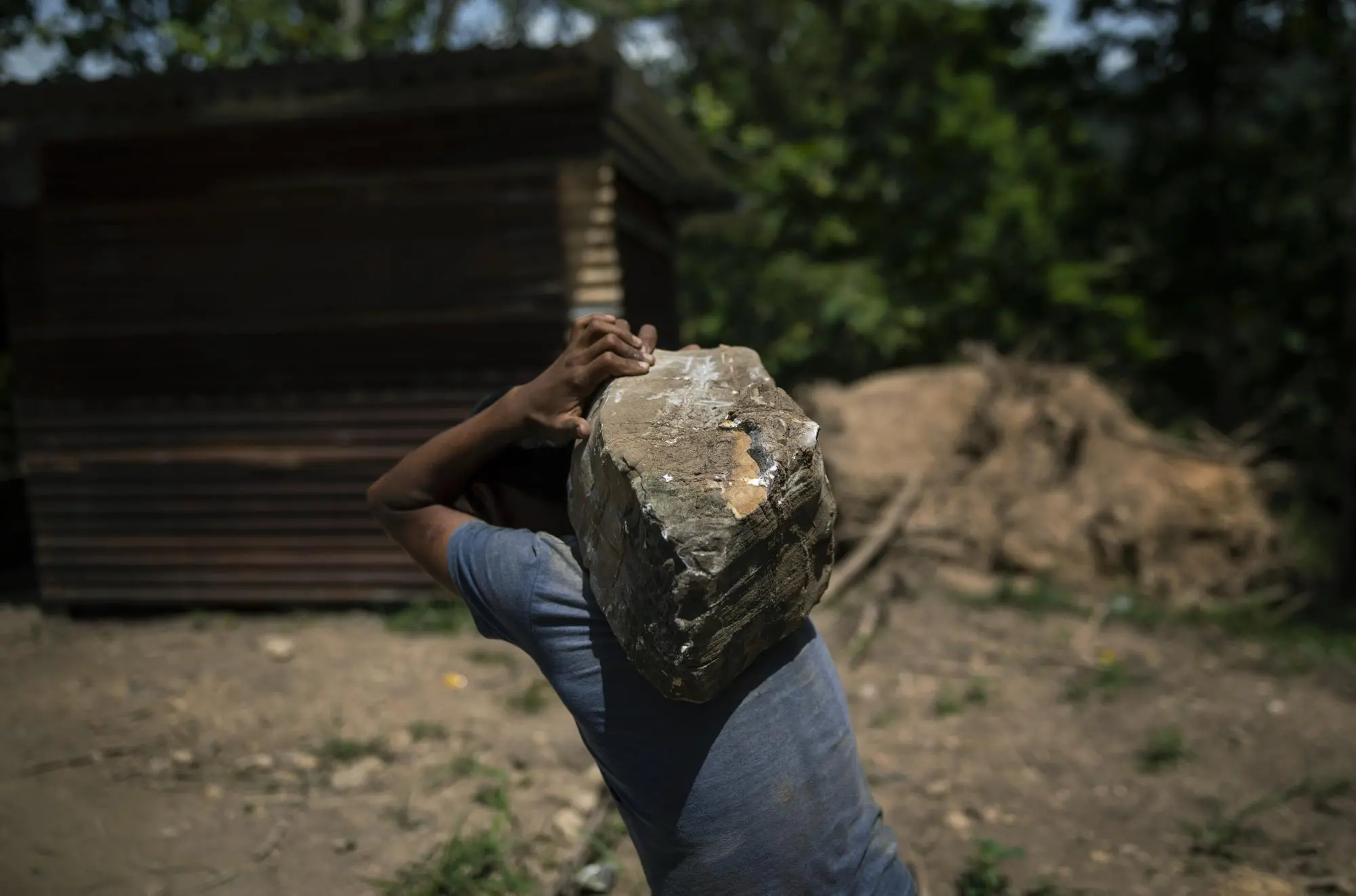 Man carries rock to help build houses
